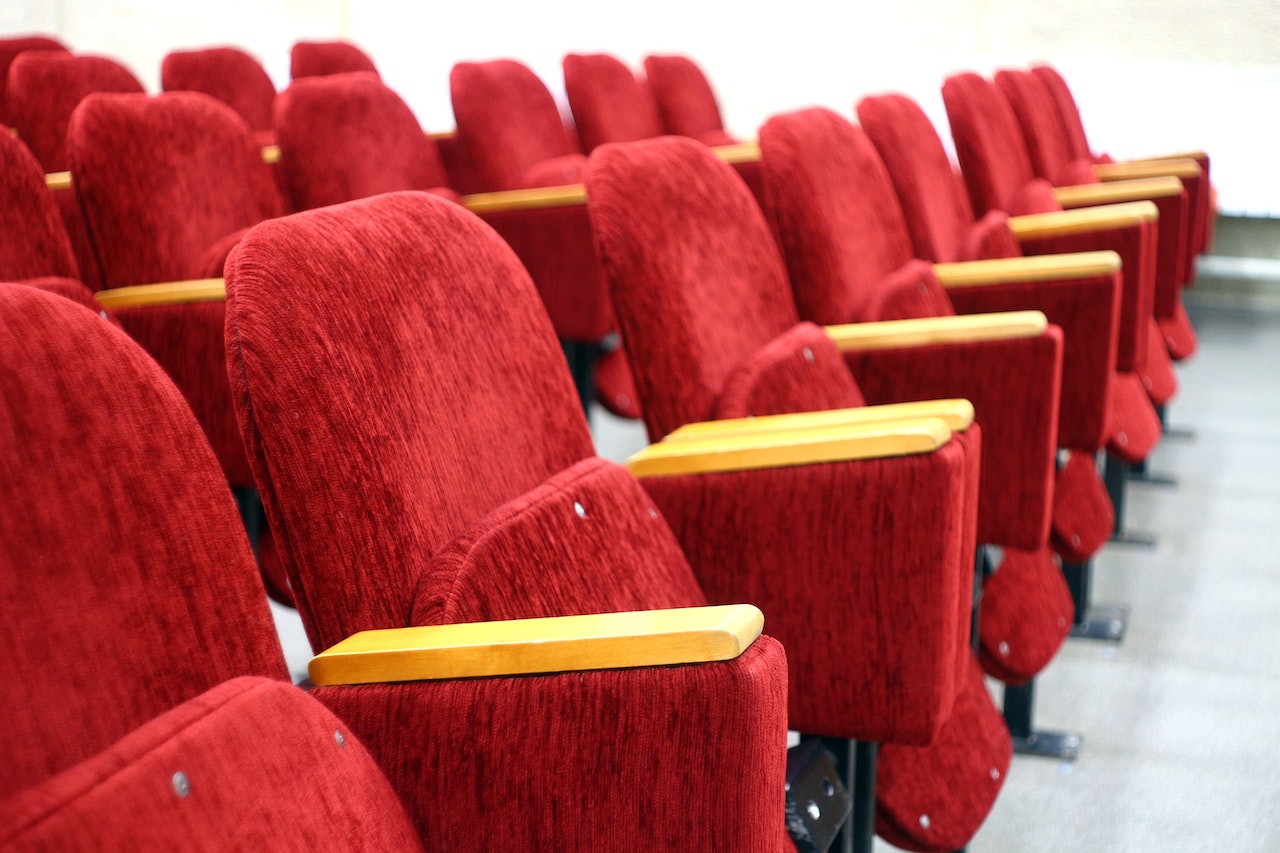 Rows of red chairs in Kumar Pacific movie hall by Kumar Realty